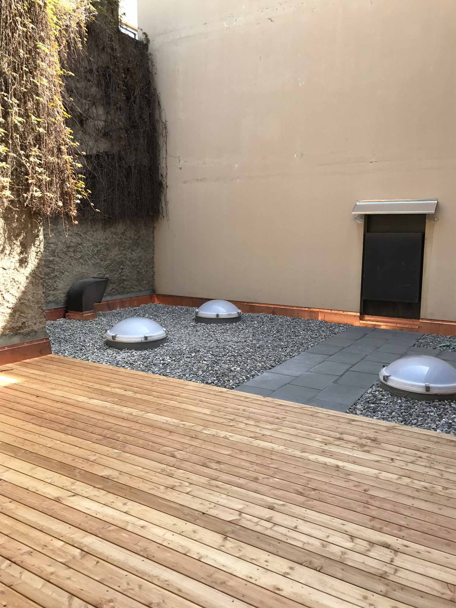 Flachdach mit Holzterrasse, Kiesbett und Lichtkuppeln